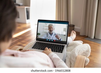 Close Up Over Shoulder View Of Pregnant Young Woman Talk Speak On Video Call On Laptop With Male Doctor. Female With Baby Bump Have Virtual Digital Consultation With Gynecologist On Computer At Home.