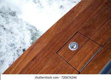 Close Up Overhead Perspective Of A Teak Wood Swim Step On The Stern Of A Luxury Motorboat, With Foaming Water And Waves In The Background