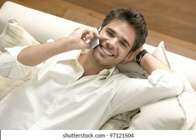 Close Up Overhead View Of A Professional Man Using A Cell Phone While Laying Down On A Sofa.