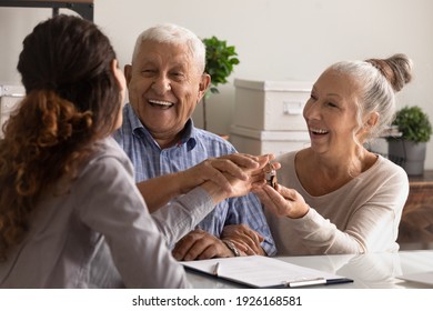 Close Up Overjoyed Mature Couple Received Keys From Realtor Manager, Smiling Older Wife And Husband Purchased New Own Apartment, Happy Elderly Family Homeowners Making Successful Deal At Meeting