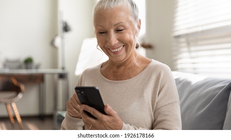 Close Up Overjoyed Mature Woman Using Phone, Sitting On Couch, Browsing Smartphone Apps, Looking At Screen, Senior Female Chatting With Relatives Online, Shopping, Having Fun With Mobile Device