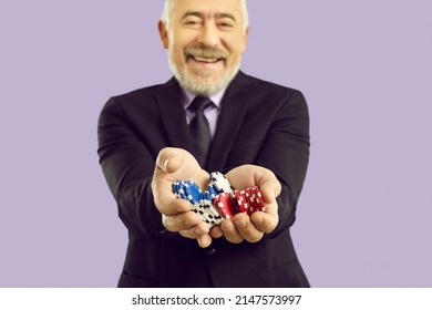 Close Up Of Overjoyed Old Man Handful Of Casino Chips Celebrate Win. Smiling Senior Male Poker Player Enjoy Gambling And Entertainment Activity. Violet Studio Background. Luck And Fortune.