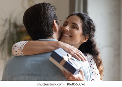Close up overjoyed wife hugging husband, thanking for romantic present, surprise, happy attractive young woman holding gift box with bow, couple celebrating anniversary, birthday or Valentines day