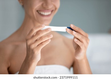 Close up of overjoyed young woman after shower do medical quick pregnancy ovulation test, get positive result, smiling female excited about future maternity confirmation, fertility, ivf concept - Powered by Shutterstock