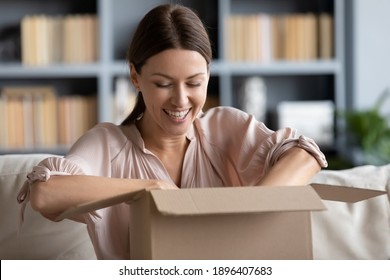 Close up overjoyed young woman unpacking cardboard box at home, satisfied customer received awaited parcel with online store order, sitting on couch, good quick delivery service concept