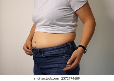 Close up of overweight young woman with fat belly after childbirth, pants doesn't fit