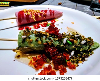 Close up The Paan Kulfi and strawberry kulfi with decorate with some gems and cherry on the white plate