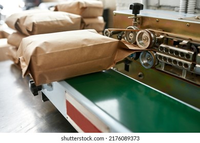 Close up of pack machine with paper package of coffee beans at table on factory. Coffee process making and production. Small business. Modern automated manufacturing equipment. Nobody - Shutterstock ID 2176089373