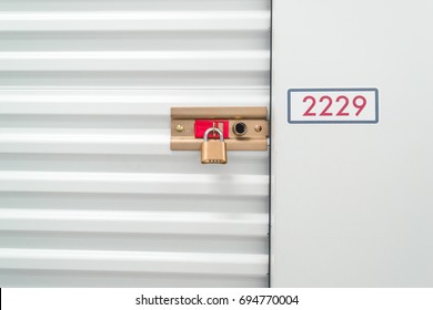 Close Up Of A Pad Lock And Red Number On A White Storage Unit.