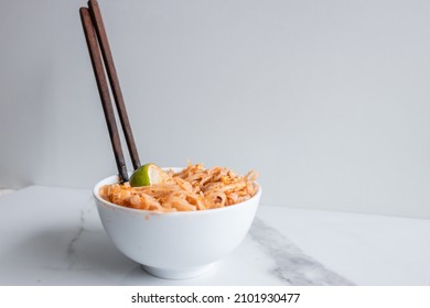 Close Up Of A Pad Thai Bowl With Chopsticks On A White Background.