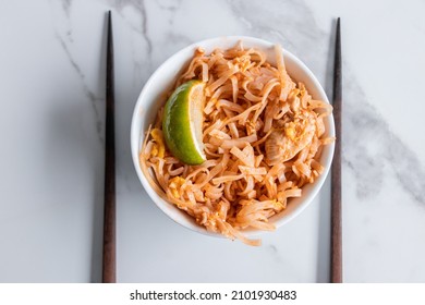 Close Up Of A Pad Thai Bowl With Chopsticks On A White Background.