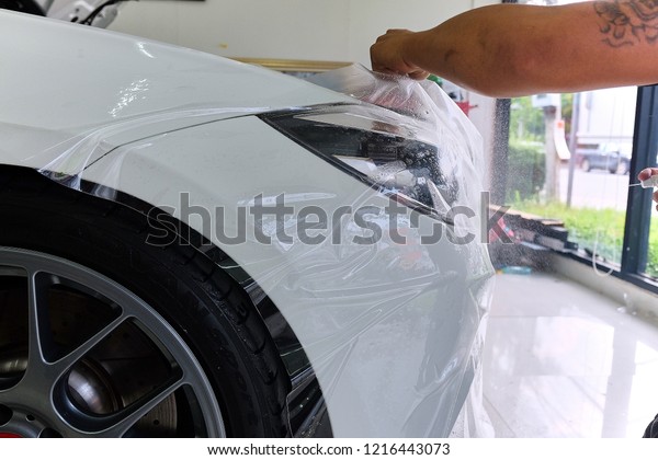 Close up of paint protection film installation\
on side mirror of modern luxury car. PPF is polyurethane film\
applied to painted of car to protect the paint from stone chips,\
bug splatter, and\
abrasion