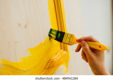 Close Up Paintbrush In Woman's Hand Painting The Wooden Door With Yellow Paint, Creative Design House Renovation Theme, DIY Concept