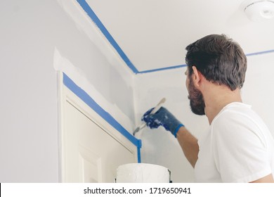 Close Up Of Painter Hands With Gloves Painting The Wall Edge By Door Frame. 