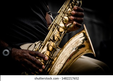 A close up of a pair of hands holding a saxophone.  - Powered by Shutterstock