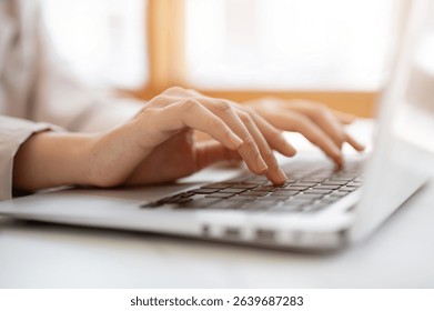 Close up of a pair of hands typing both hands on laptop's keyboard at white table beside glass wall in the cafe. Working or Study, Chilling Outside.