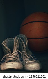 Close Up Pair Of Old Worn Sport Sneakers Shoes And One Basketball Ball In Locker, Low Angle View