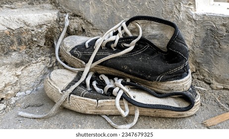 Close up pairs of worn-out and forgotten shoes discarded by their owners. Black and white canvas shoes.  - Shutterstock ID 2347679325