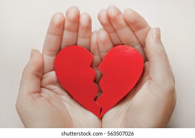 Close up of paper broken heart on white wooden background