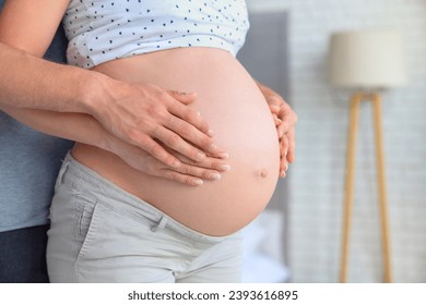 Close up of parents hands touching pregnant belly at home. Future parents, expectant pregnant woman with father dad husband waiting for a baby. Parenting - Powered by Shutterstock