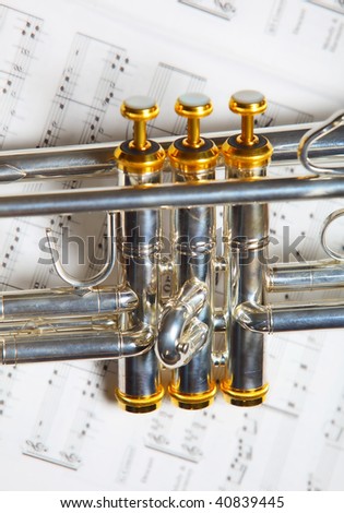 Close up part of silver B-flat trumpet on top of music sheet
