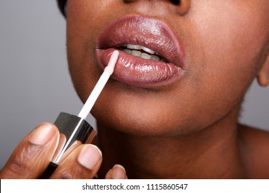 Close Up Partial Portrait Of Beautiful African American Woman Applying Shiny Lip Gloss 