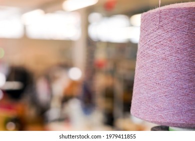 Close Up Partial View Of A Large Reel Of Natural Pink Cashmere Yarn In A Factory With A View To A Blurred Interior With Copyspace