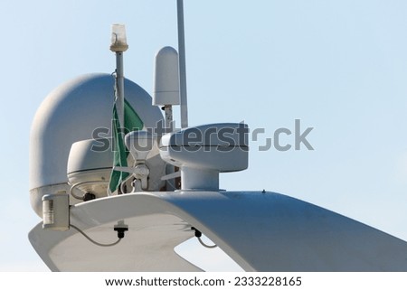 Close up partial view of white high quality leisure motor boat with mounted radar spotlight horn flag and antennas as concept for orientation and communication on the high seas