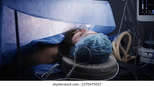 Close up of patient during surgery. Adult man lies on table under anesthesia and with breathing tube in modern operating room. Professional surgeons operate patient using laparoscopy instruments. - Powered by Shutterstock