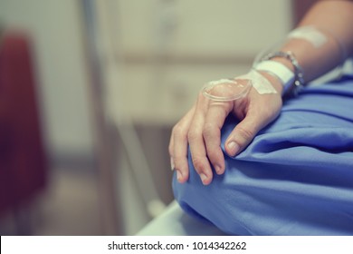 close up patient man hand with label and drip (IV saline tube) waiting for operation of chemotherapy medical , healthcare and cancer day concept