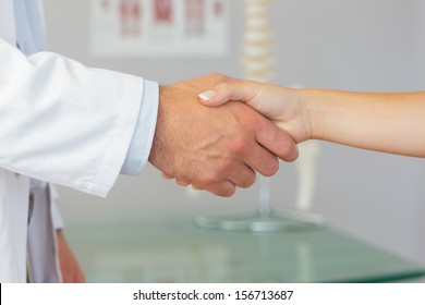 Close up of patient shaking hands with doctor in bright office - Powered by Shutterstock