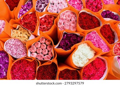 A close up pattern captures a dense collection of vibrant carnation bouquets in orange wrapping at the Flower Market in Hong Kong.