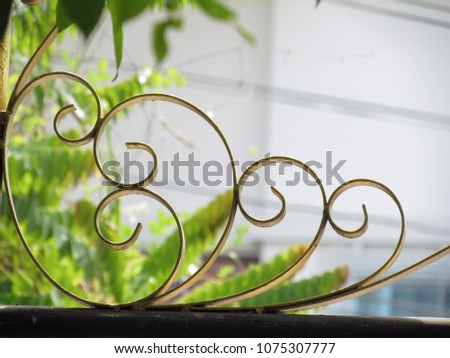 Close up pattern of wrought iron fence gate with nature background.
