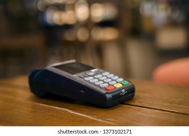close up payment machine on the table for paying bill by at table , contactless purchase concept