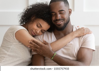 Close up of peaceful beautiful millennial biracial woman embrace sleep on man lover shoulder, happy african American couple hug cuddle enjoy romantic intimate moment at home together - Powered by Shutterstock