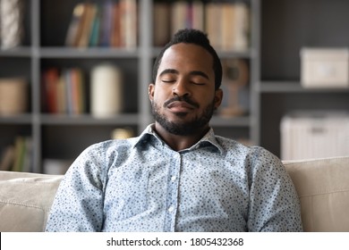 Close up peaceful satisfied African American man sleeping, sitting on cozy couch in modern living room, mindful calm young male daydreaming, relaxing on comfortable sofa with closed eyes at home - Powered by Shutterstock