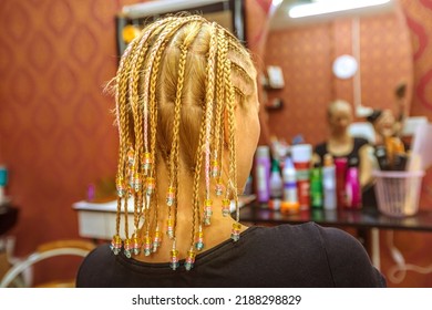 Close Up Pearl Braids To A Young Blonde Woman With Dreadlocks In A Thai Beauty Center, Looking The Mirror.