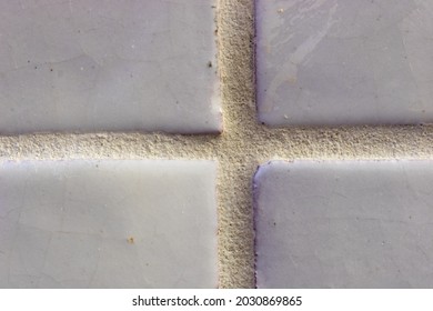 Close Up Of A Pearl White Tile. The Background Texture Features Course Grout Lines And Smooth And Weathered Ceramic Tile.