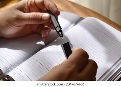 close up a pen and a pen cap in the hands of a person on the background of a notebook