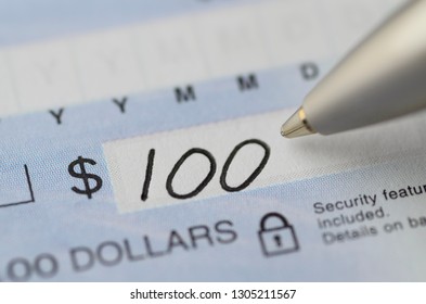 Close Up Of Pen Writing The Dollar Amount Begining With 100 On A Cheque With Security Features