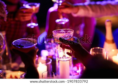 Close up of people drinking cocktails in restaurant. People having good time, cheering and drinking cold cocktails, enjoying friendship together in restaurant, close up view on hands.