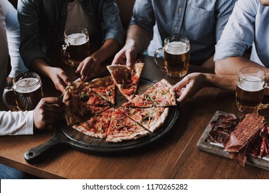 Close up of People Hands Taking Slices of Pizza. Smiling Friends Eating Pizza and Drinking Beer at Restaurant or Pizzeria. Friends Partying and Eating Pizza. Drinking Beer. - Powered by Shutterstock