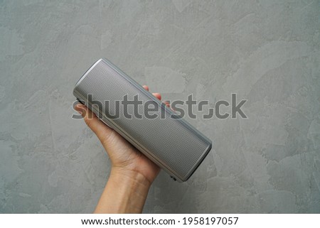 close up people hold Bluetooth speaker in hand for music connection with loft wall background