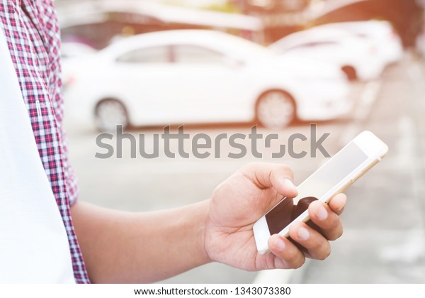 close up people man hand using a mobile smart\
phone call a car mechanic ask for help assistance because car broke\
in parking outdoor. standing wait beside broken car background.\
soft focus.
