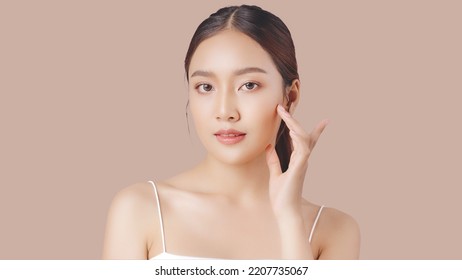 Close up perfect beauty face of young beautiful Asian woman massages her face gently with fingertips. Face cream commercial advertising concept.