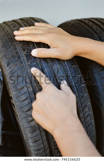 Close up of person\
checking examining car tyre on the shelf abstract transportation\
background. Automobile warehouse business, factory production.\
Protector surface texture