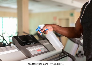 Close Up Of A Person Cleaning A Gym Machine With Disinfectant. Selective Focus. Space For Text.