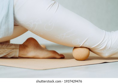Close up of person doing quadriceps muscle fascia release with a large cork massage ball
