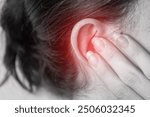 close up of a person with a earache, holding their ear, painful area highlighted in red, tinnitus problem, health problems, hearing problems or hearing loss concept.