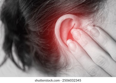 close up of a person with a earache, holding their ear, painful area highlighted in red, tinnitus problem, health problems, hearing problems or hearing loss concept.